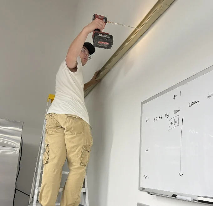 Core Comfort technician drilling near the ceiling during installation preparation